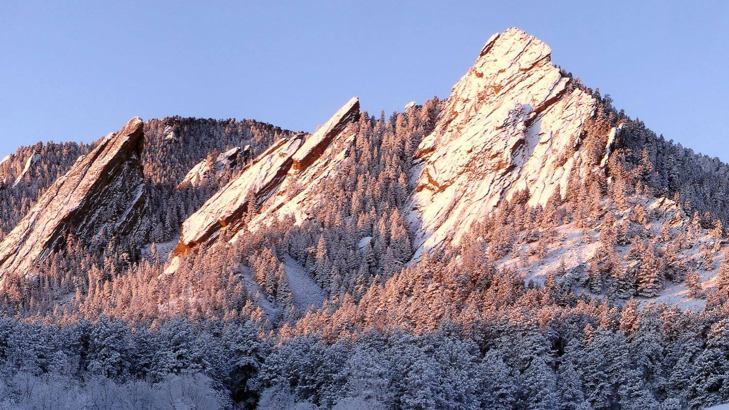 The Flatirons rock formations rising above Boulder, Colorado at sunrise, dusted with snow — EMF radiation testing and shielding help for Boulder homes