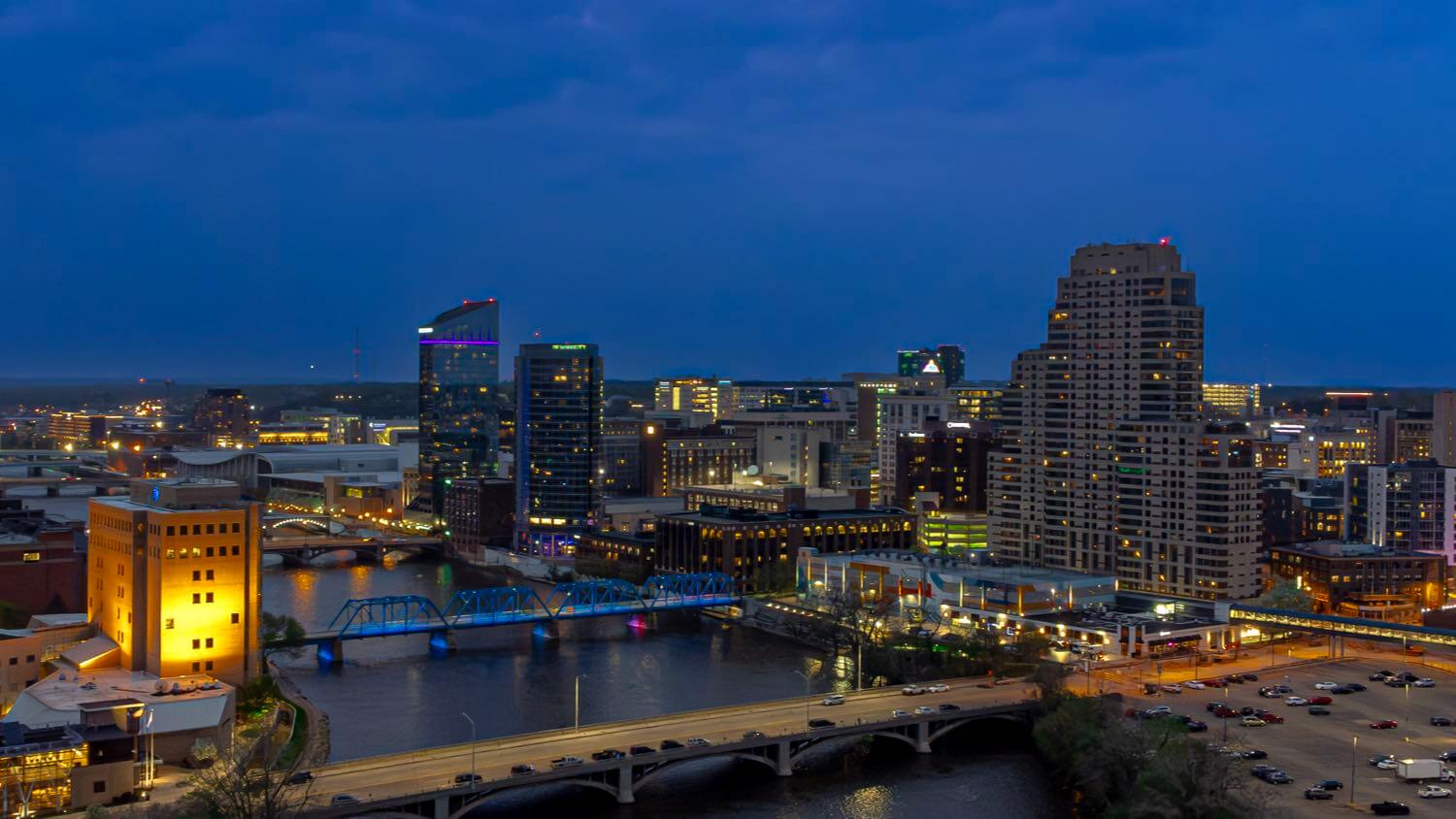 Downtown Grand Rapids, Michigan skyline with the Grand River and a pedestrian bridge at dusk — EMF radiation testing and shielding help for Grand Rapids homes