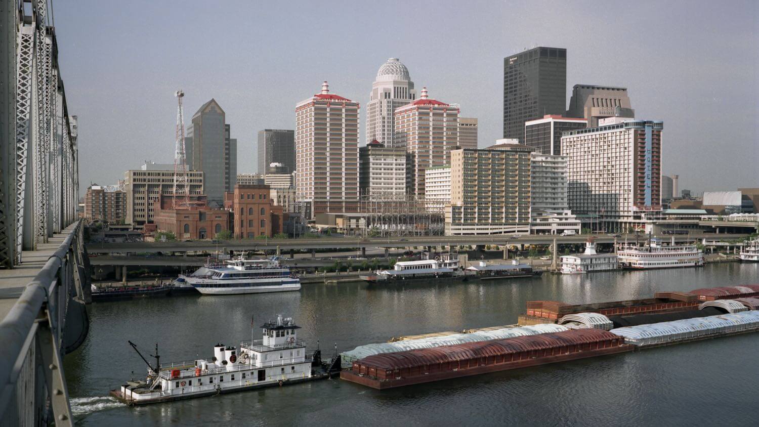 Downtown Louisville, Kentucky skyline along the Ohio River with a barge &mdash; EMF radiation testing and shielding help for Louisville homes