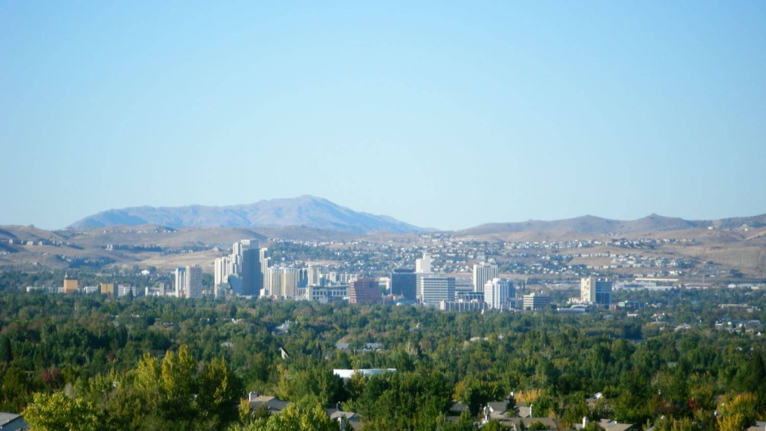 The downtown Reno, Nevada skyline in the high-desert valley with surrounding mountains &mdash; EMF radiation testing and shielding help for Reno homes