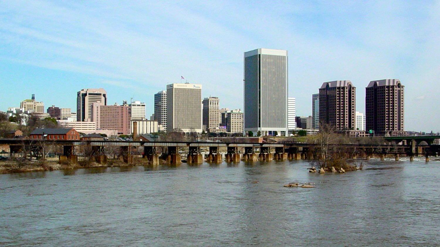 The downtown Richmond, Virginia skyline across the James River with a railroad bridge in front — EMF radiation testing and shielding help for Richmond homes