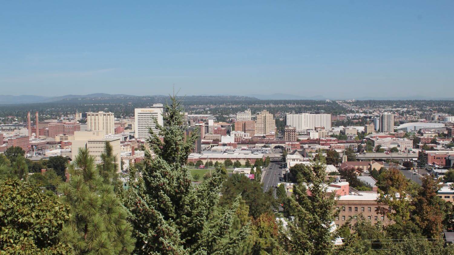 The downtown Spokane, Washington skyline seen from a pine-lined South Hill overlook — EMF radiation testing and shielding help for Spokane homes